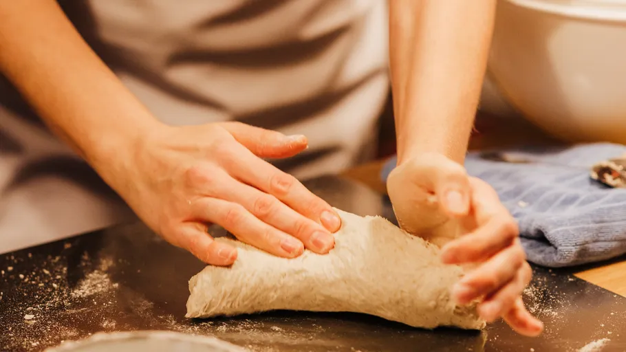 Hands kneading dough on a floured surface.