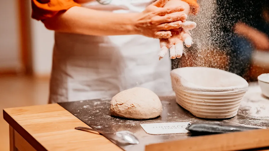 Person preparing dough at wooden counter.