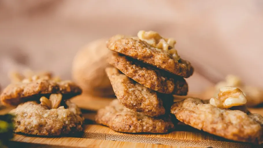 Walnut cookies stacked on wooden board.