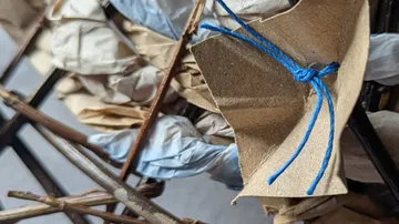 Brown paper flower tied with blue string.