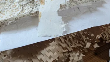 Zerrissenes Papier mit Blumenmuster auf Holz.
