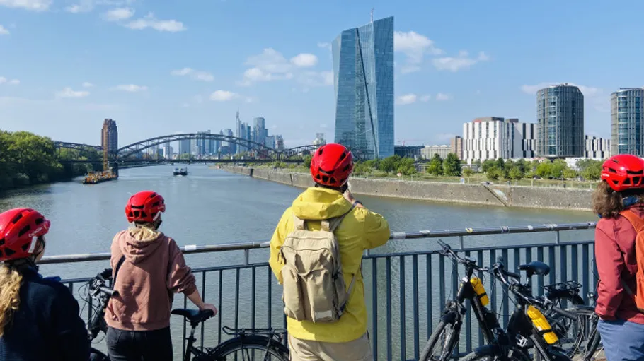 Personen mit Fahrrädern auf Brücke mit Skyline.