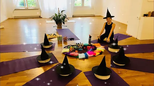 Person mit Hexenhut sitzt auf Yogamatte.