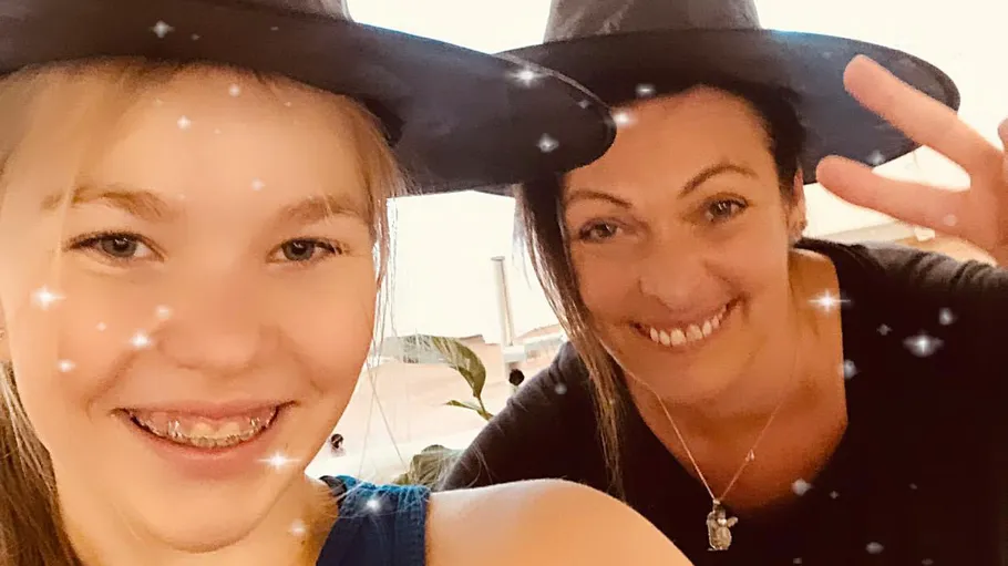 Two people smiling, wearing hats indoors.