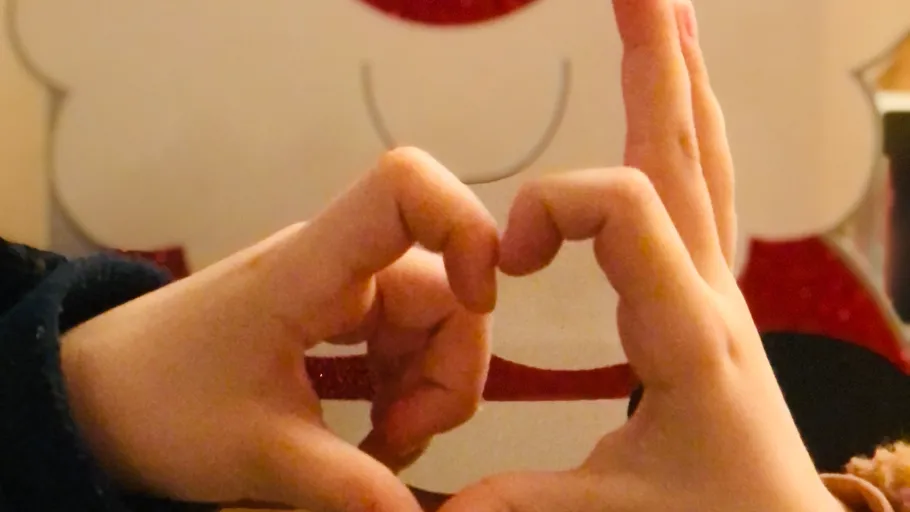 Hands form a heart shape, Santa background.