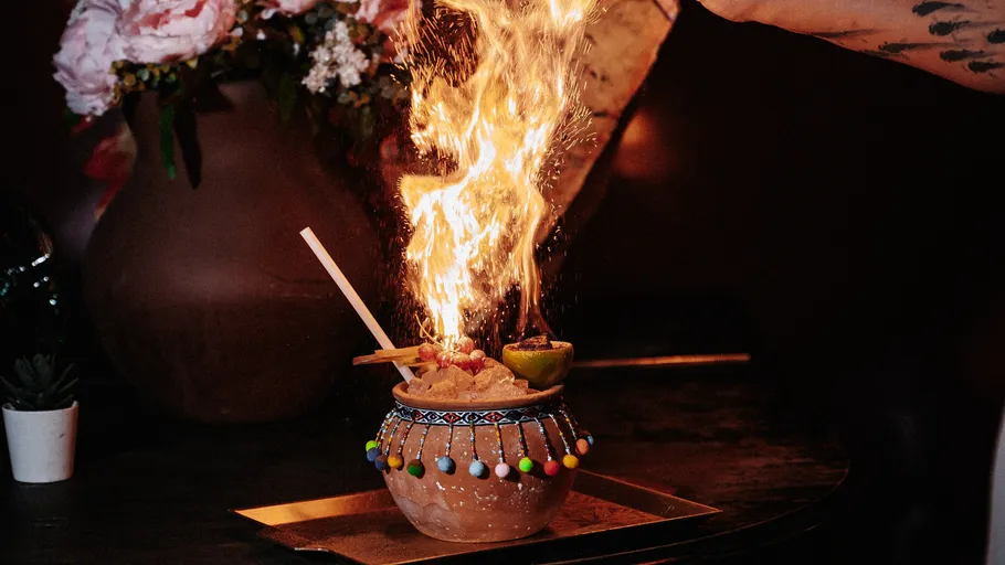 Hand streut Gewürz, erzeugt Flammen über Cocktail.