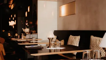 Leere Restauranttische mit Lampen, schummrig beleuchtet.
