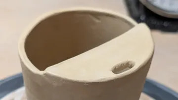 Clay pot with spout on table.
