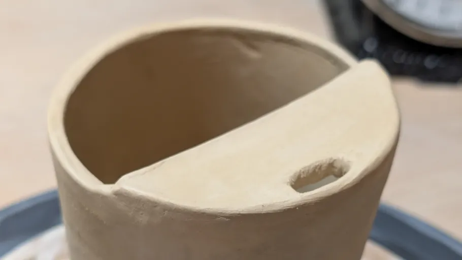Clay pot with spout on table.