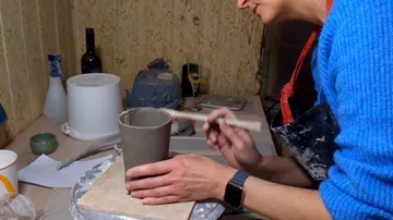 Person crafting pottery in a workshop environment.