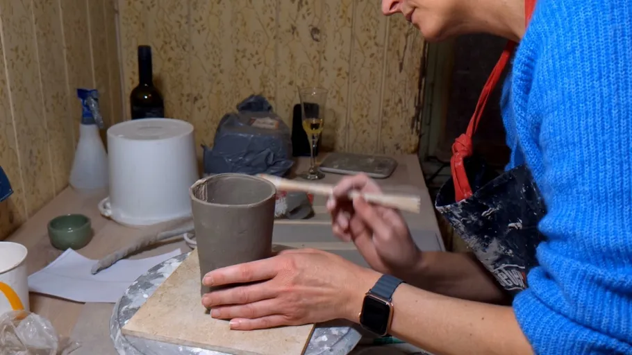 Person crafting pottery in a workshop environment.