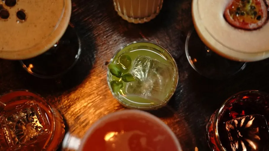 Verschiedene Cocktails auf einem Holztisch angeordnet.