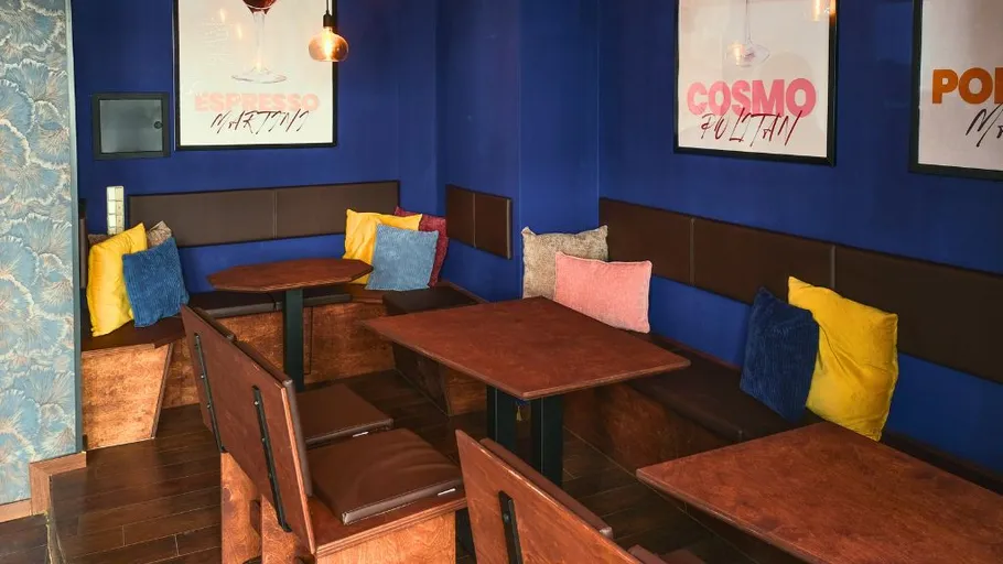 Cozy cafe with colorful cushions and blue walls.