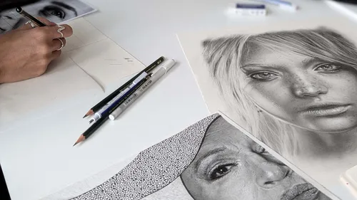 Artist drawing portraits on a white table.