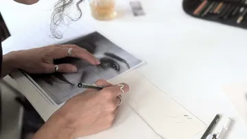 Person sketching a face from a photo.