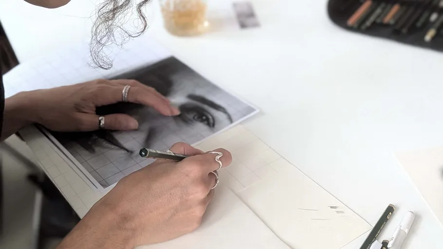 Person sketching a face from a photo.