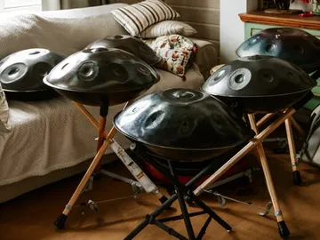 Fünf Handpan-Instrumente stehen vor einem Coucharrangement.