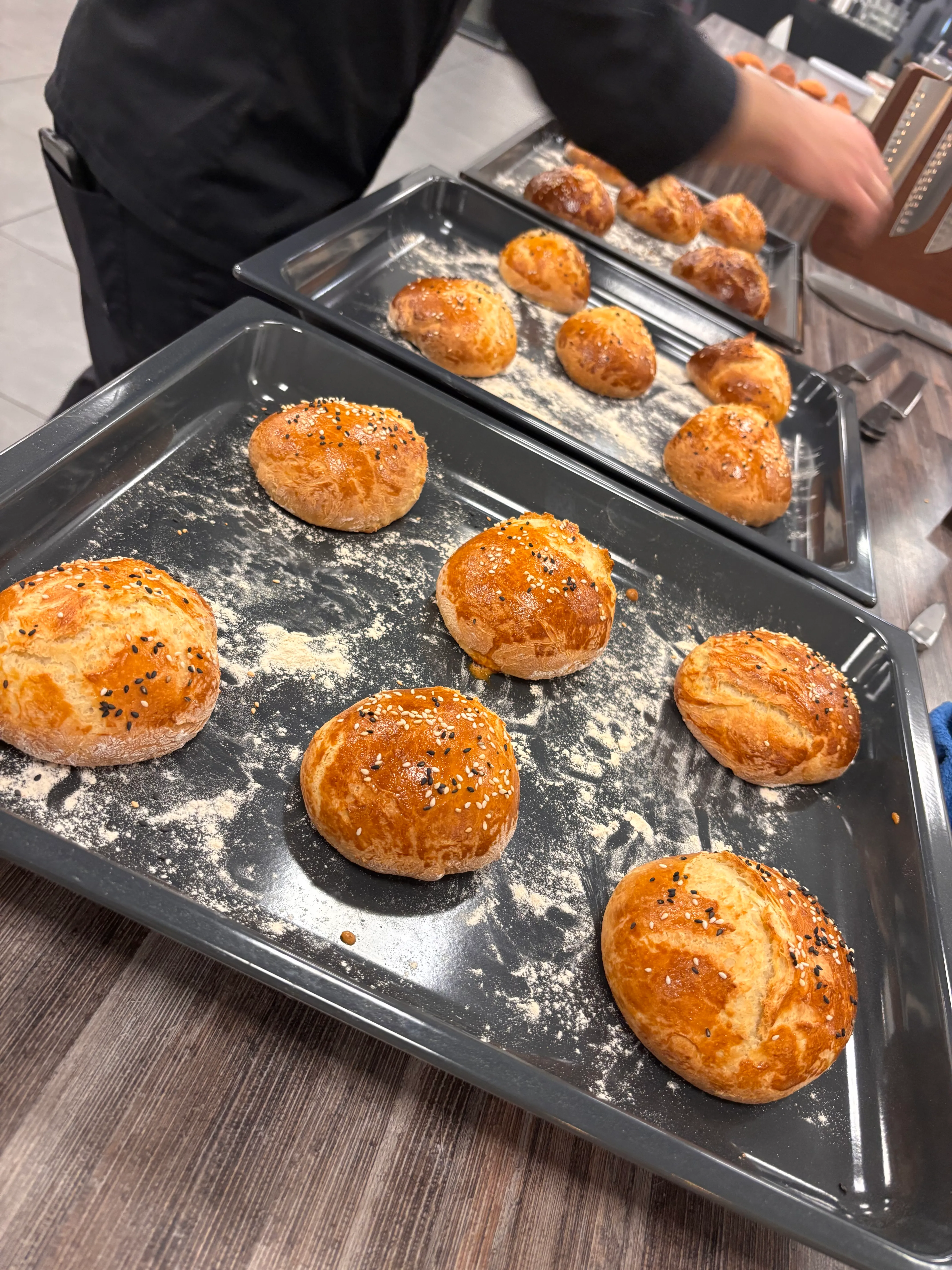 Freshly baked buns on trays in kitchen.