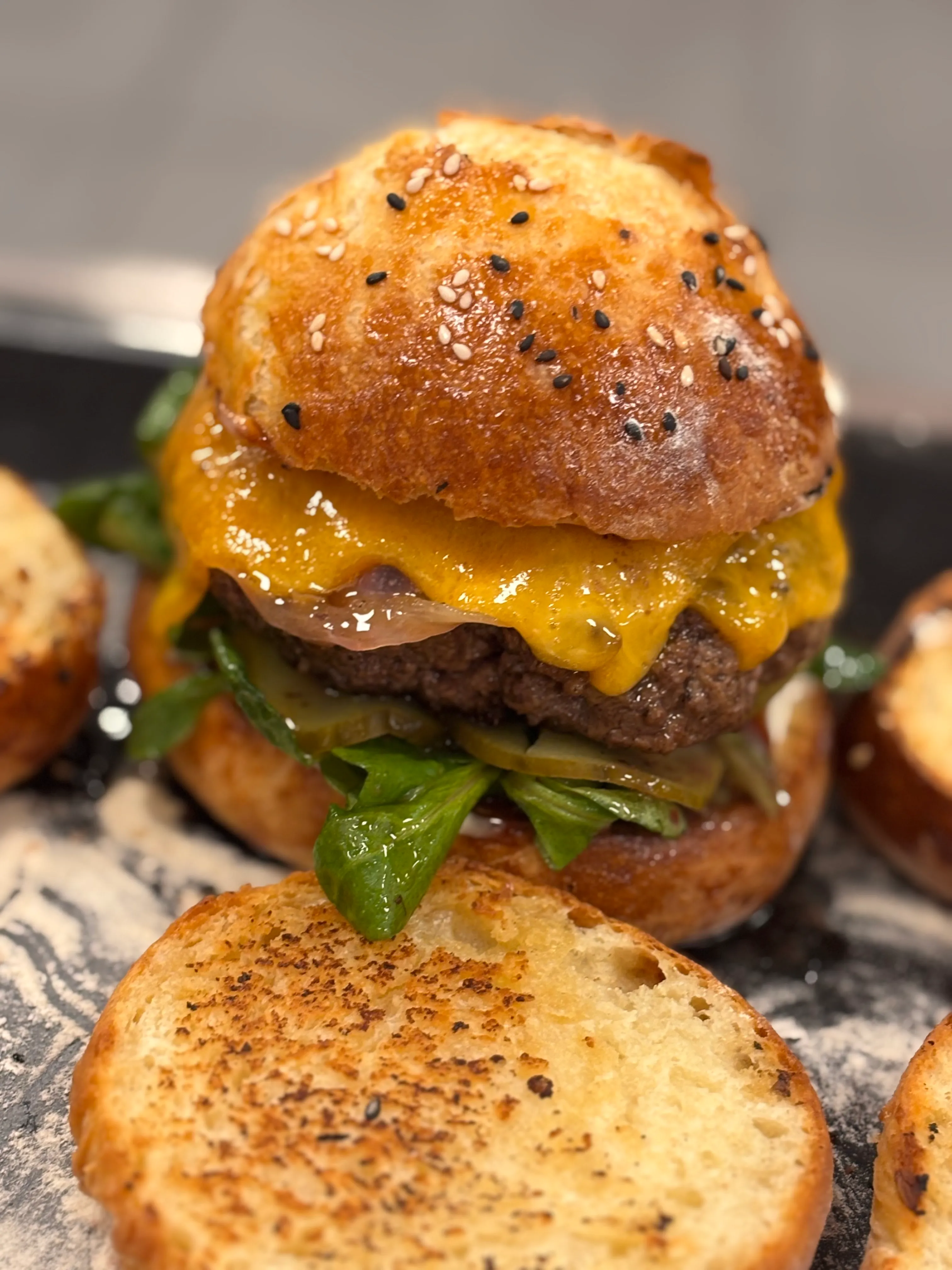 Cheeseburger with leafy greens on bun.