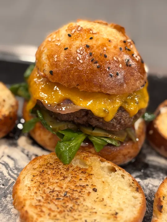 Cheeseburger mit Blattgemüse auf Brötchen.