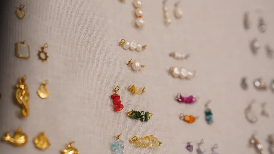 Various small jewelry hanging on beige fabric.