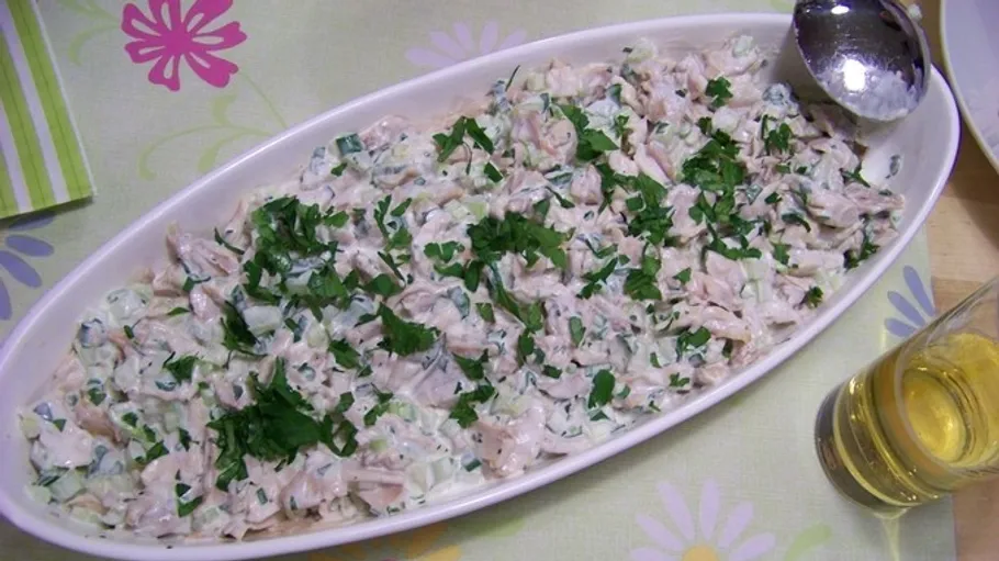 Chicken salad with herbs on floral tablecloth.