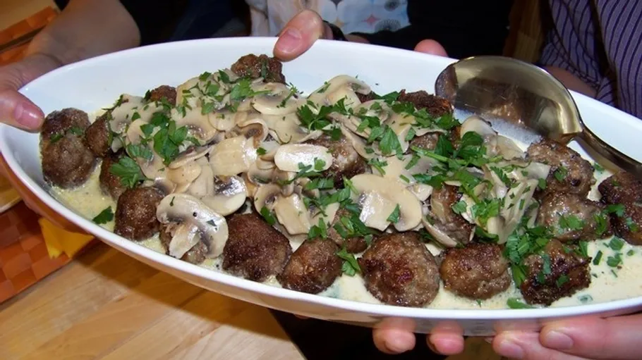 Meatballs with creamy mushroom sauce, garnished, served.