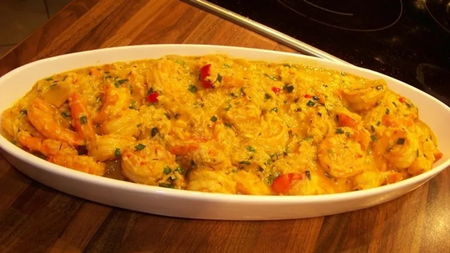 Shrimp in yellow sauce, in white dish.