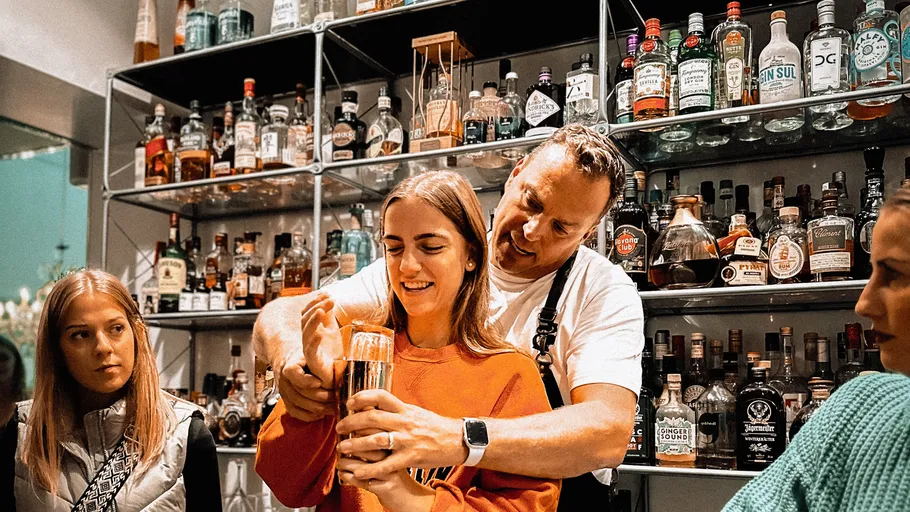 Man helps woman mix drink in bar.