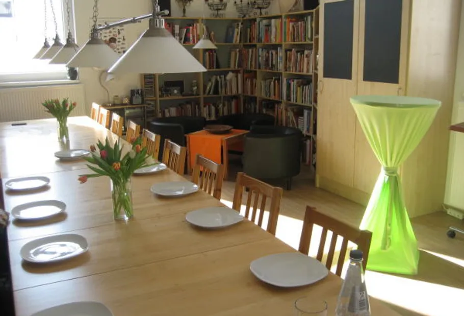 Dining table set with plates, flowers, bright room.