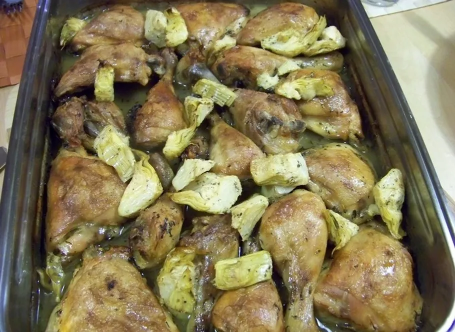 Roasted chicken and artichokes in baking dish.