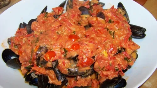 Mussels in tomato sauce in a white bowl.