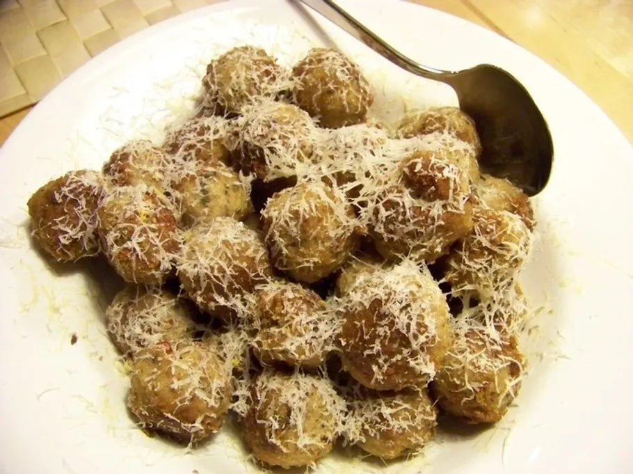 Meatballs with grated cheese on a plate.
