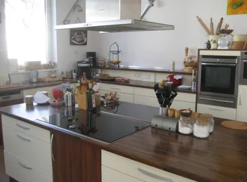 Moderne Küche mit Holzarbeitsplatten, Utensilien und Geräten.