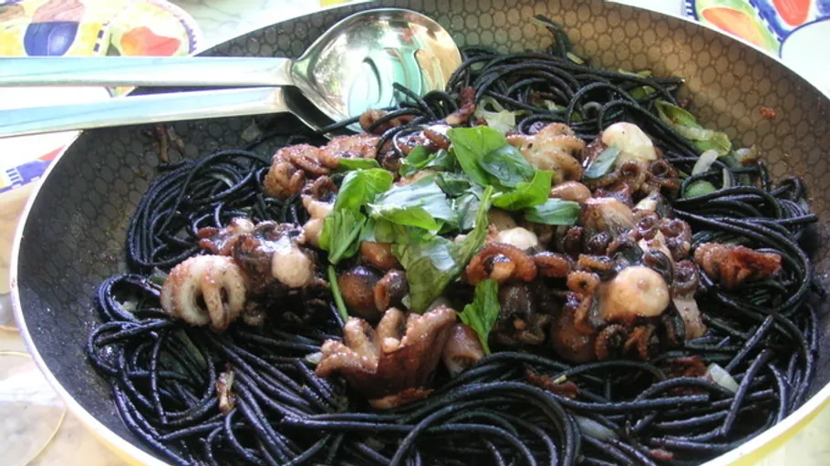 Black pasta with seafood in a pan.