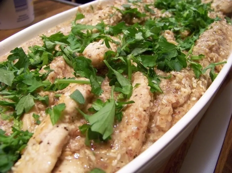 Chicken strips topped with chopped parsley in dish.