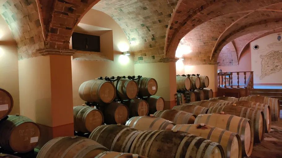 Wooden barrels stored in a brick cellar.