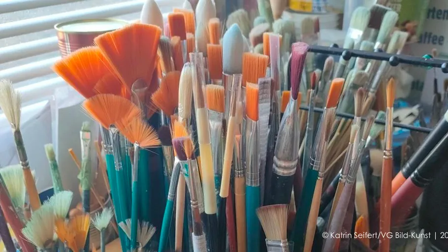Various paintbrushes in holder near window.