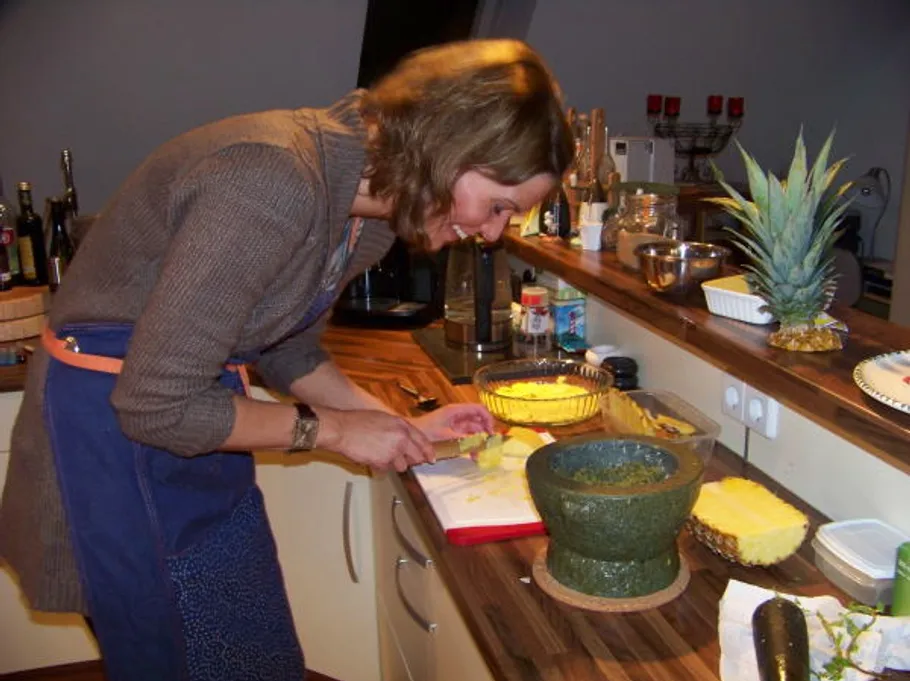 Woman slicing pineapple in a kitchen.
