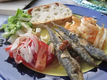Plate with fish, shrimp, salad, and bread.