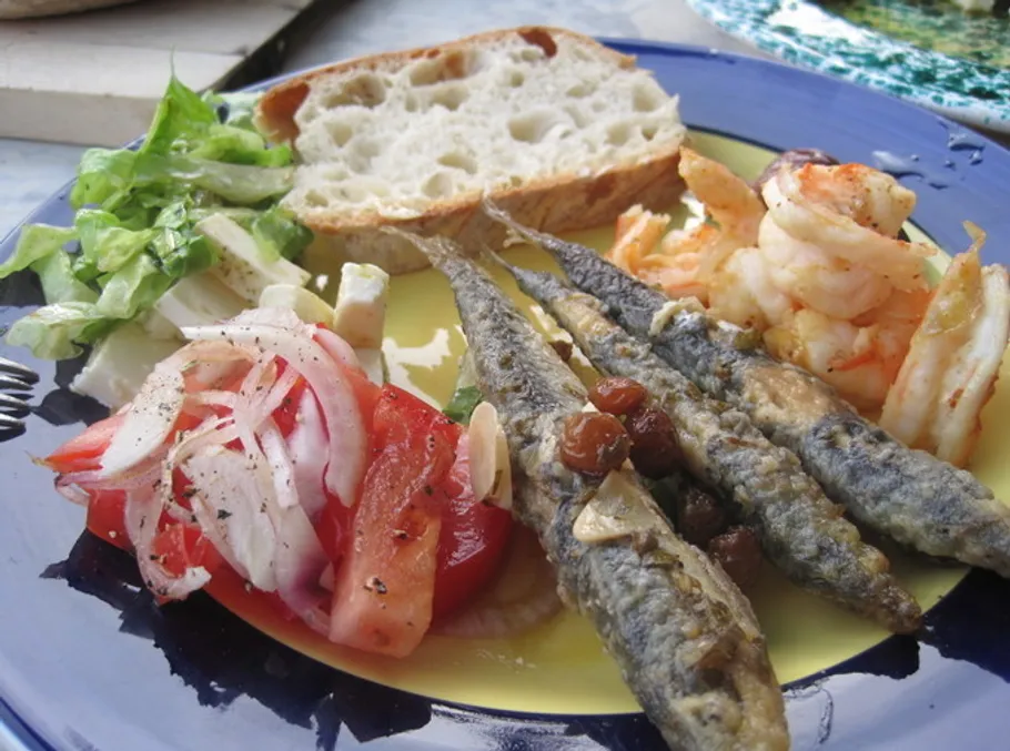Teller mit Fisch, Garnelen, Salat und Brot.
