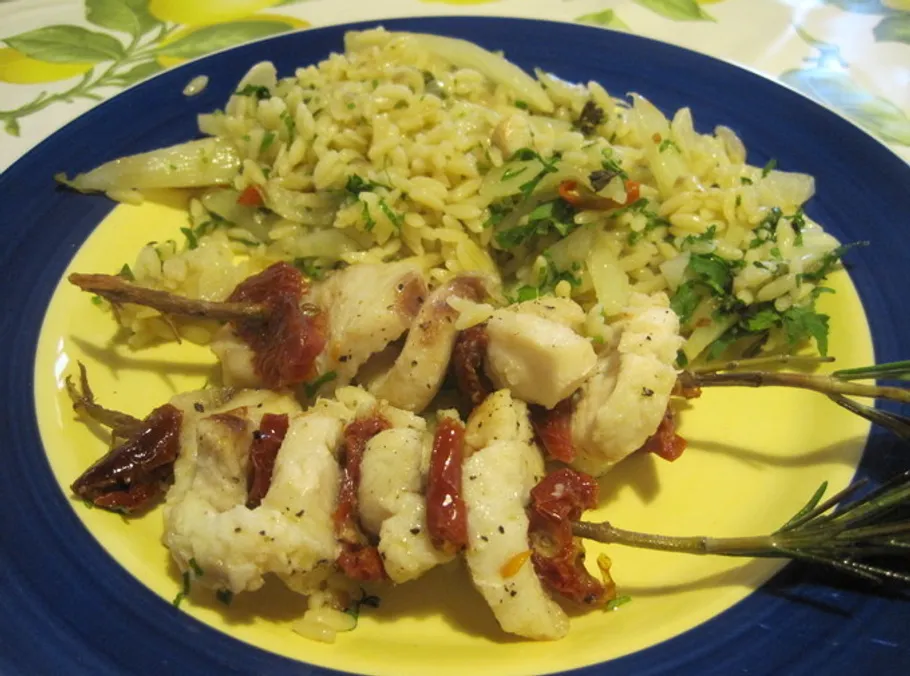 Chicken skewers with rice on plate.