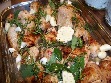 Gebratenes Huhn mit Kräutern und Knoblauch in einer Pfanne.