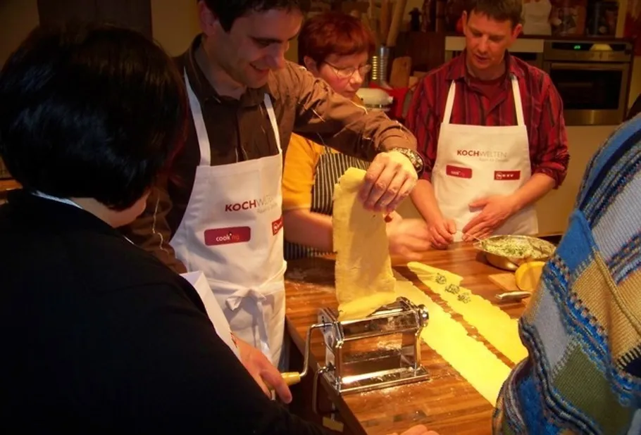 Leute machen Pasta mit einer Nudelmaschine.