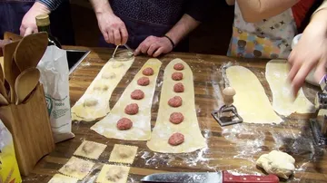 People making ravioli with pasta dough and filling.