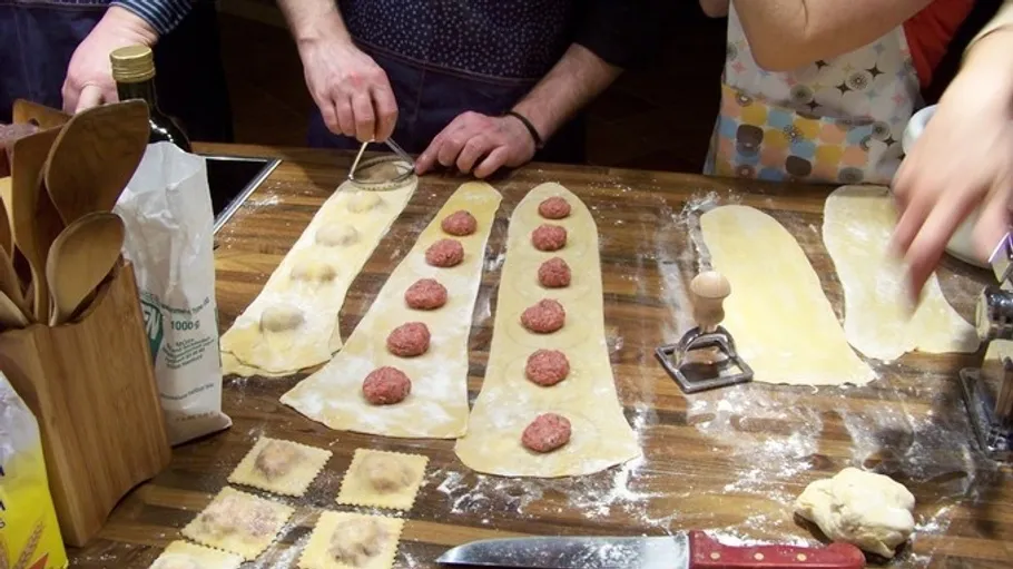 People making ravioli with pasta dough and filling.