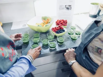 Green drinks in glasses sit on a countertop.