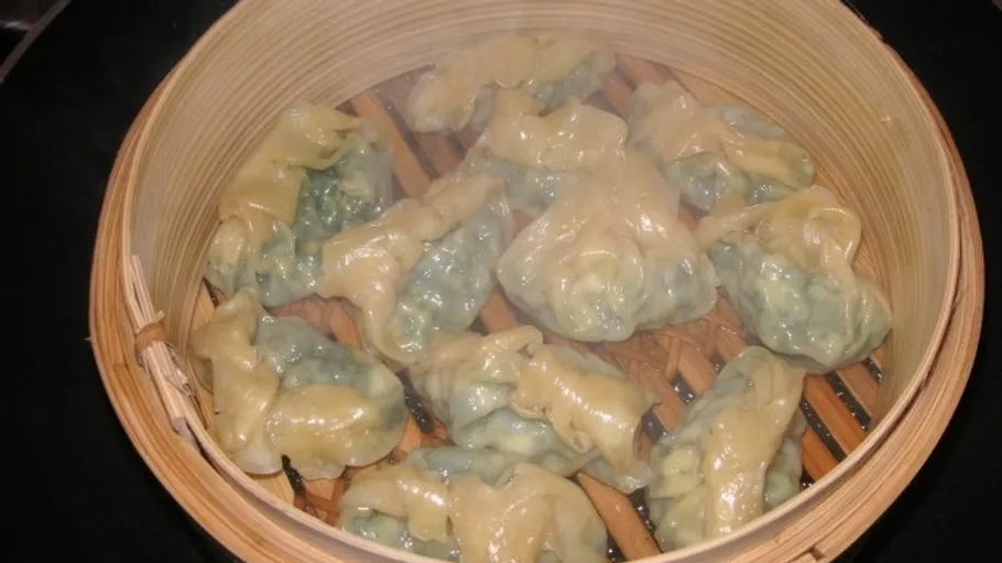 Steamed dumplings in bamboo steamer, hot kitchen.