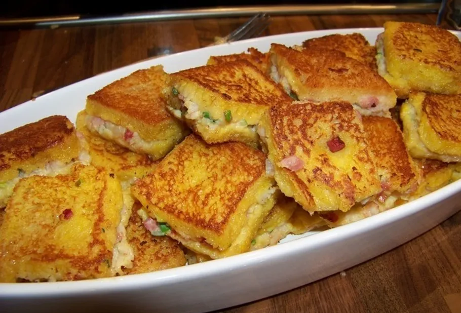 Grilled sandwiches stacked in a white dish.