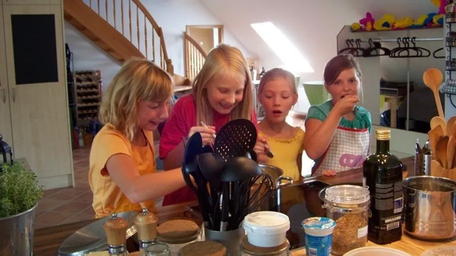 Four children cooking together in a kitchen.